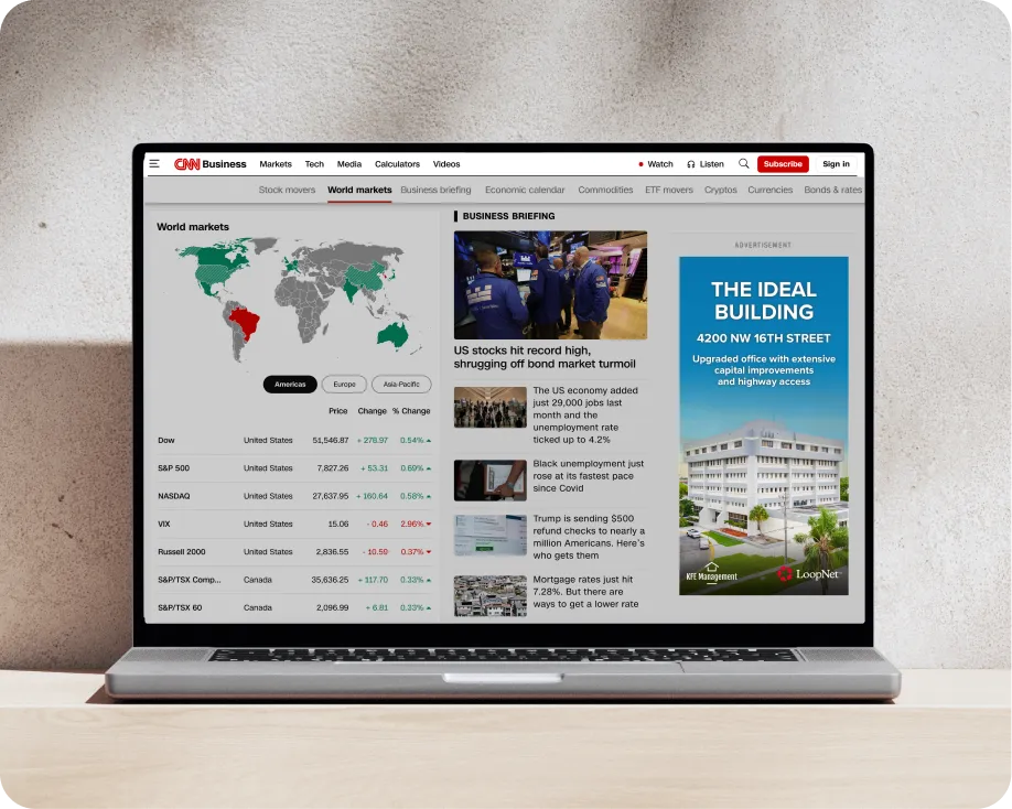 Laptop showing a CNN Business world markets page with a LoopNet property ad in the sidebar.